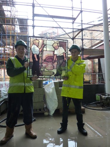 Caption 'Two of the Graham Construction Joinery Apprentices holding a replica of a Stephen Adam Stained Glass Panel of the Iron Moulders'